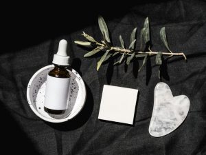 Allantoin skincare cream and comfrey plant on dark linen