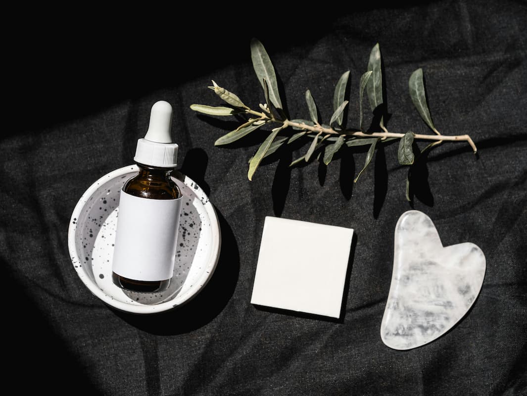 Allantoin skincare cream and comfrey plant on dark linen