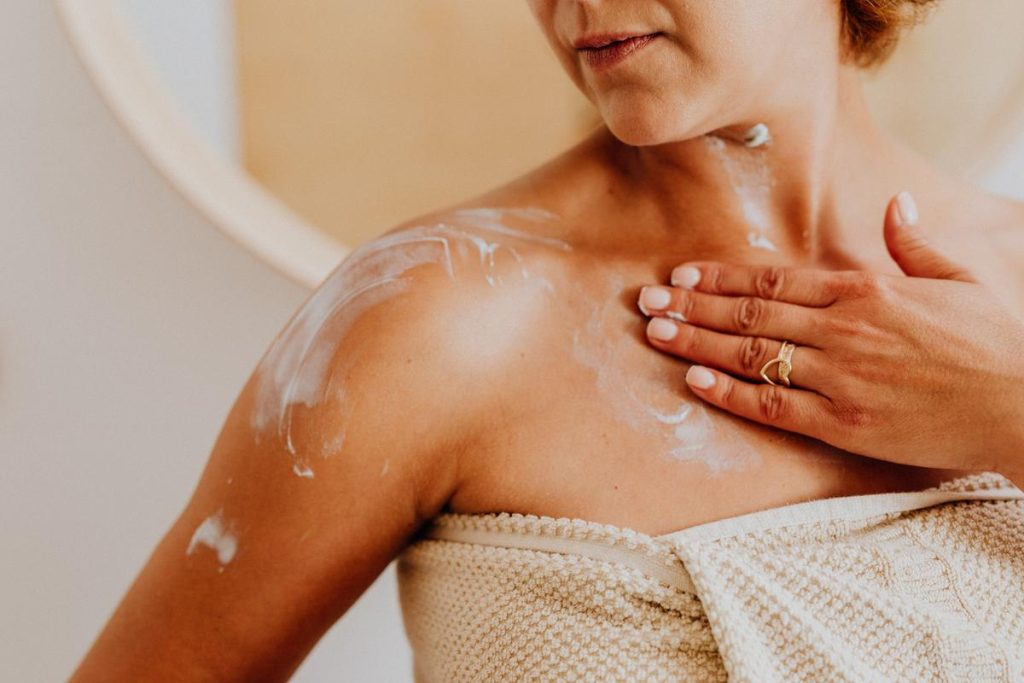 Woman applying ceramide-rich moisturiser to her shoulder as part of a gentle psoriasis treatment